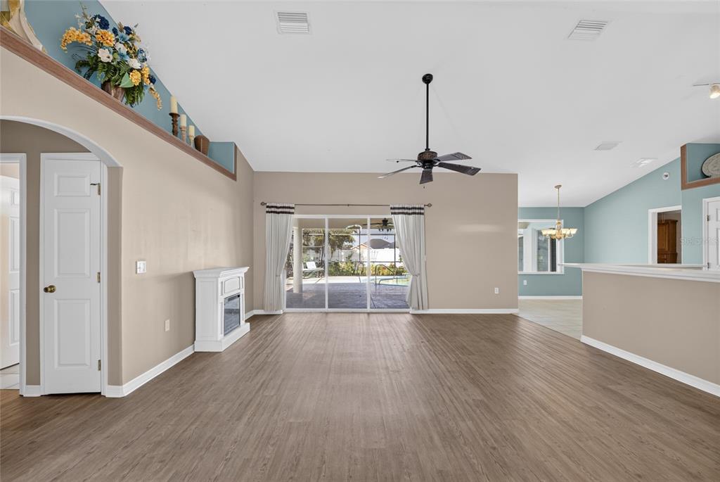A spacious living room features wood-look flooring, a white fireplace, and sliding glass patio doors — 8328 SW 56TH TERRACE, OCALA, FL