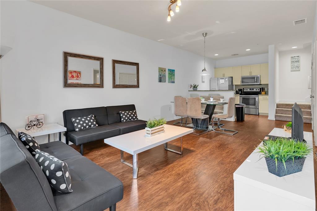 An open-concept living and dining area features dark sofas, a white coffee table, and kitchen — 3210 OYSTER LANE, KISSIMMEE, FL