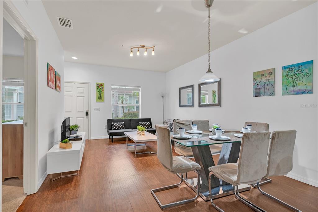 A dining area and living room with wood-look flooring, white walls, and modern furniture — 3210 OYSTER LANE, KISSIMMEE, FL