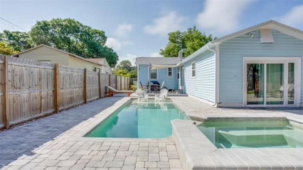 A backyard features a rectangular swimming pool, a small spa, and a light blue house — 4629 4TH AVENUE N, ST PETERSBURG, FL
