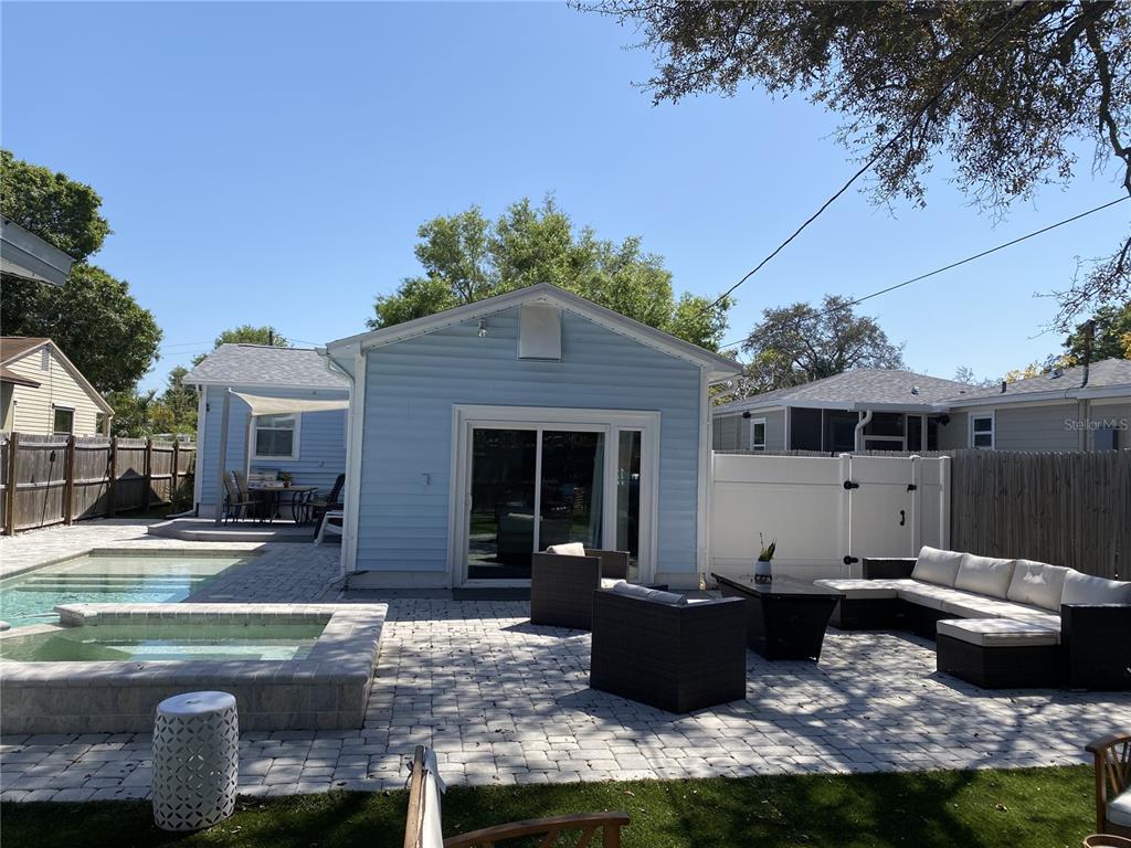A backyard patio features a swimming pool, hot tub, outdoor furniture, and a light blue house — 4629 4TH AVENUE N, ST PETERSBURG, FL