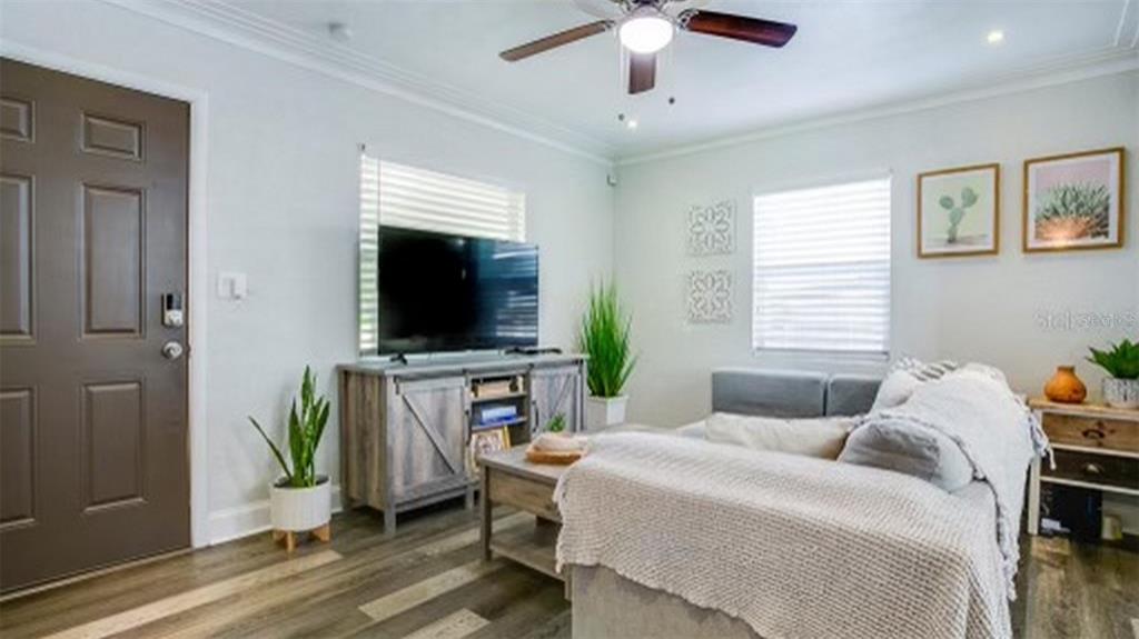 A living room features light walls, wood-look flooring, a ceiling fan, and a television console — 4629 4TH AVENUE N, ST PETERSBURG, FL