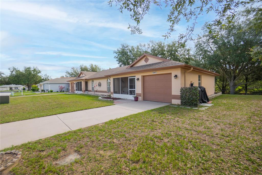 A single-story house with a tan exterior, a brown garage door, and a screened-in porch — 10407 S DREW BRYANT CIRCLE, FLORAL CITY, FL