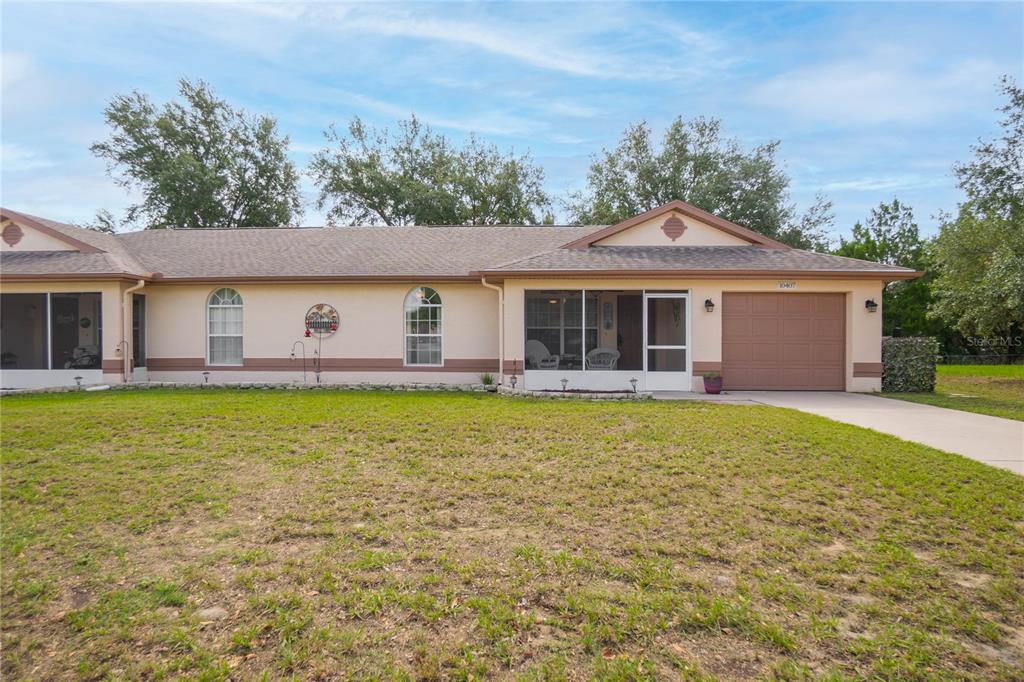 A single-story house with a tan exterior, a brown roof, and an attached garage — 10407 S DREW BRYANT CIRCLE, FLORAL CITY, FL