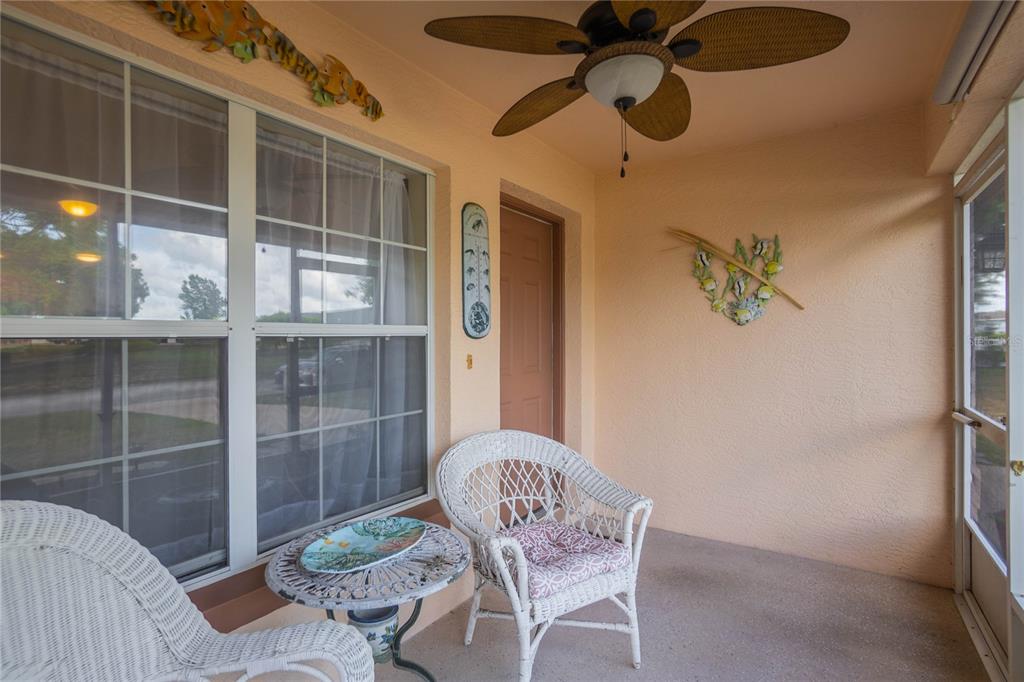 A covered patio features a ceiling fan, two white wicker chairs, and a small table — 10407 S DREW BRYANT CIRCLE, FLORAL CITY, FL