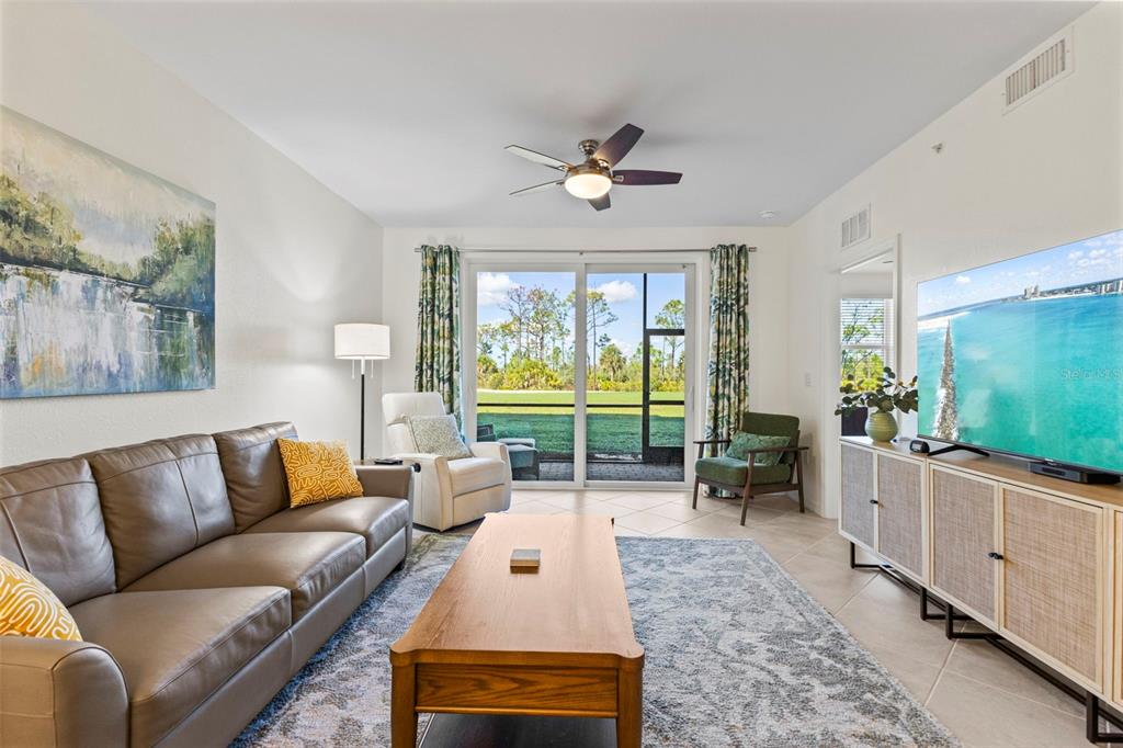 A living room features a leather sofa, wooden coffee table, and sliding doors to a patio — 12240 WELLEN GOLF STREET UNIT 104, VENICE, FL