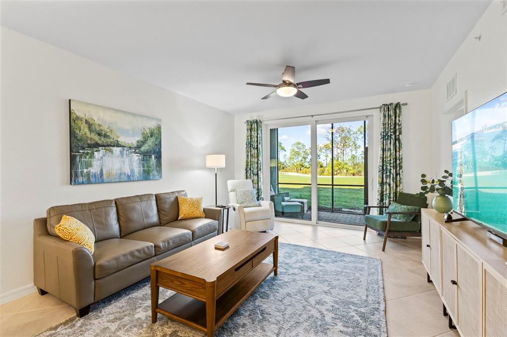 A living room features a leather sofa, wooden coffee table, and sliding doors to a patio — 12240 WELLEN GOLF STREET UNIT 104, VENICE, FL