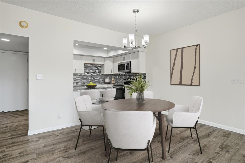 A dining area with a round table and chairs sits in front of an open kitchen — 420 64TH AVENUE UNIT 107, ST PETE BEACH, FL