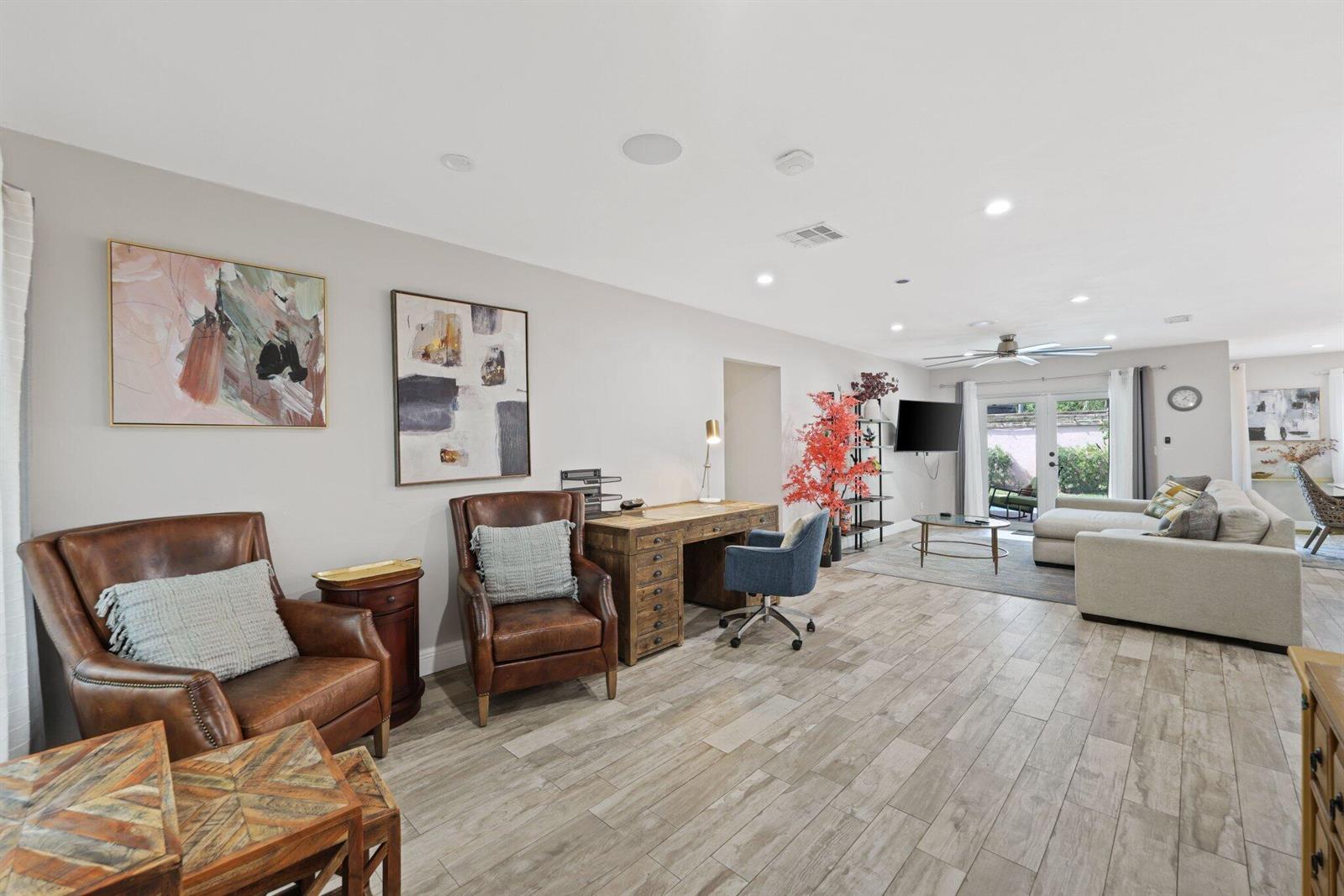 A spacious open-concept living room features leather armchairs, a wooden desk, and tile flooring — 513 Curlew Road, Delray Beach FL 33444, DELRAY BEACH, FL