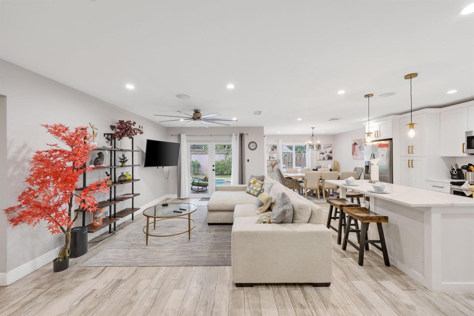 An open-concept living room and kitchen featuring a sectional sofa, dining area, and pool view — 513 Curlew Road, Delray Beach FL 33444, DELRAY BEACH, FL