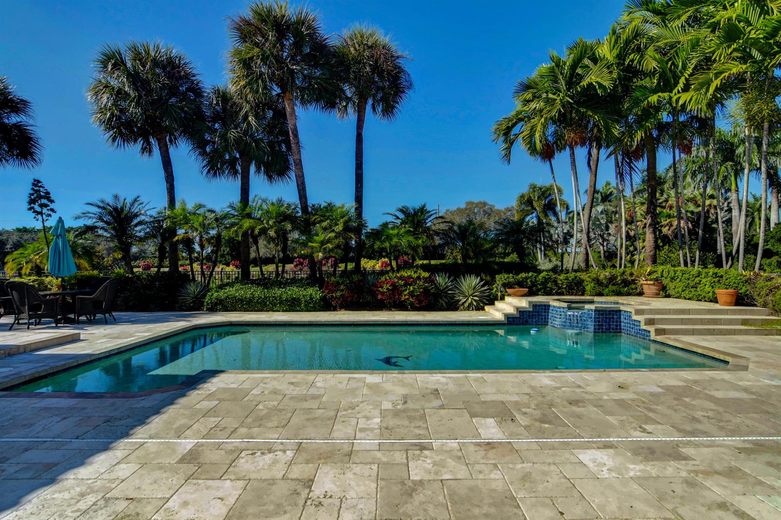 A swimming pool with a stone patio and palm trees under a clear blue sky — 4976 Bocaire Boulevard, Boca Raton FL 33487, BOCA RATON, FL