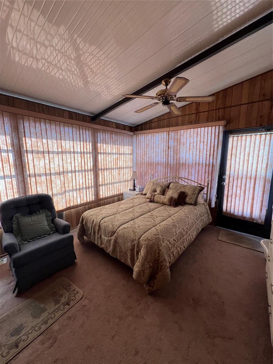 A bedroom with wood-paneled walls, a ceiling fan, a bed, and vertical window blinds — 6494 SE 54th Lane, Okeechobee FL 34974, OKEECHOBEE, FL