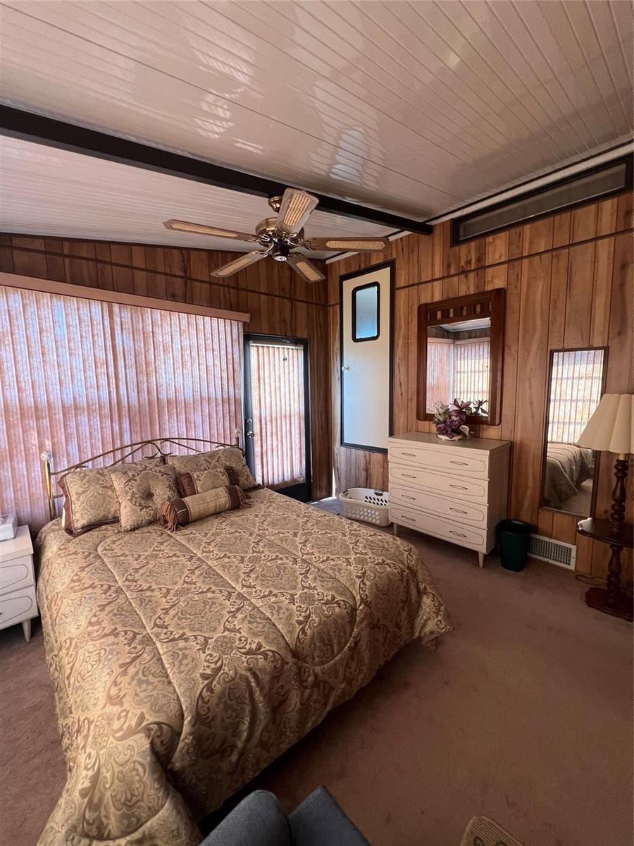 A bedroom features wood-paneled walls, a patterned bedspread, a ceiling fan, and a dresser — 6494 SE 54th Lane, Okeechobee FL 34974, OKEECHOBEE, FL
