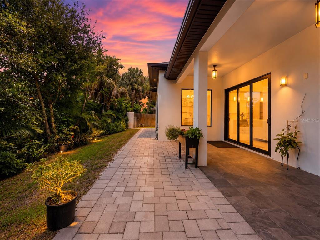 A backyard view of a modern house with a paved patio and a grassy lawn — 380 COWRY ROAD, VENICE, FL