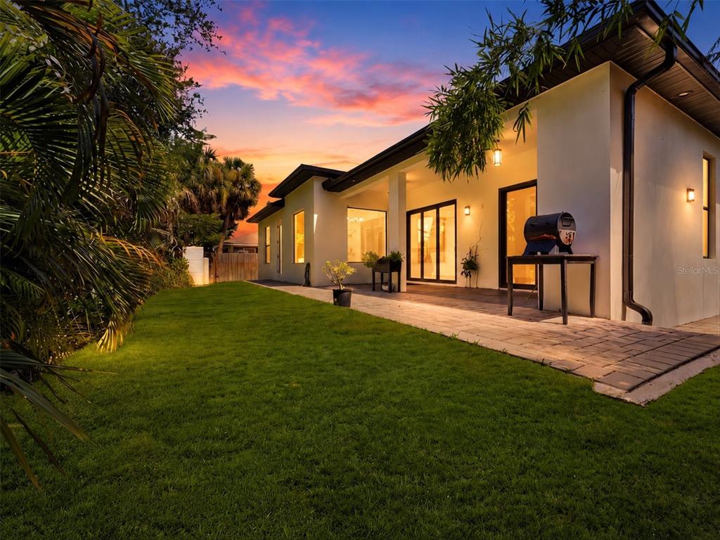 A paved patio area extends along the side of a modern house at sunset — 380 COWRY ROAD, VENICE, FL