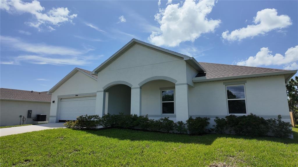 A single-story house with a white stucco exterior, a two-car garage, and a front porch — 10000 ANTLER STREET, PORT CHARLOTTE, FL