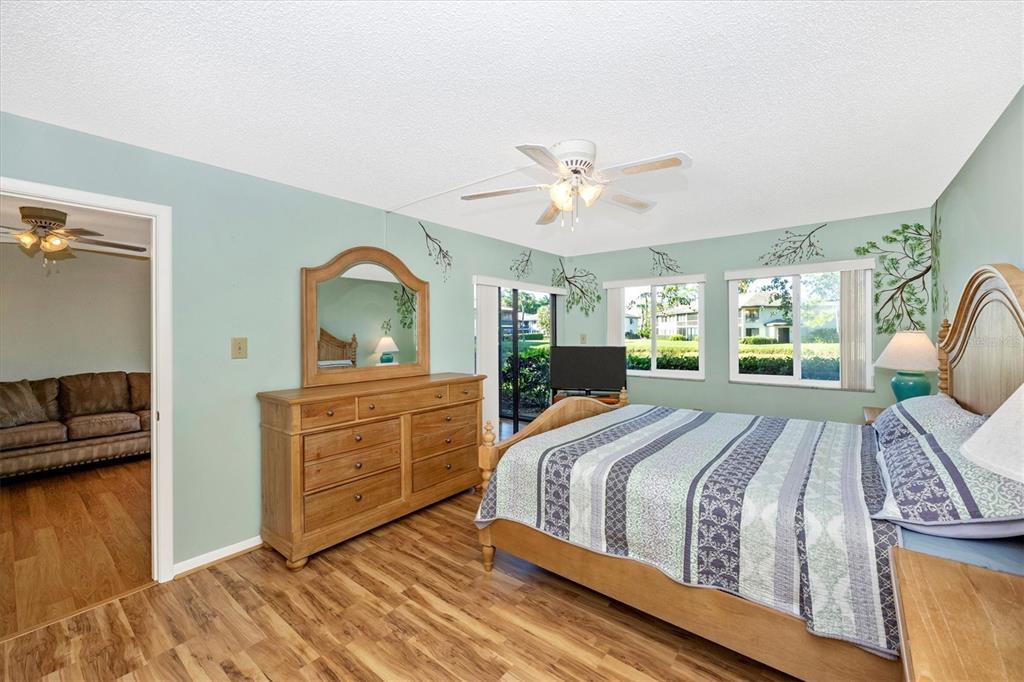 A bedroom with light green walls, wood-look flooring, a wooden bed frame, and a dresser — 5219 LAKE VILLAGE DRIVE UNIT 21, SARASOTA, FL