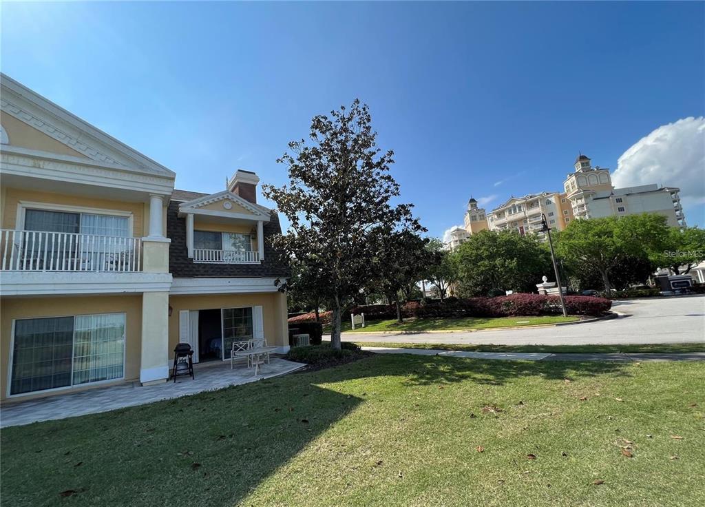 A two-story yellow building with a patio and lawn under a clear blue sky — 1301 SEVEN EAGLES COURT UNIT 1301, REUNION, FL