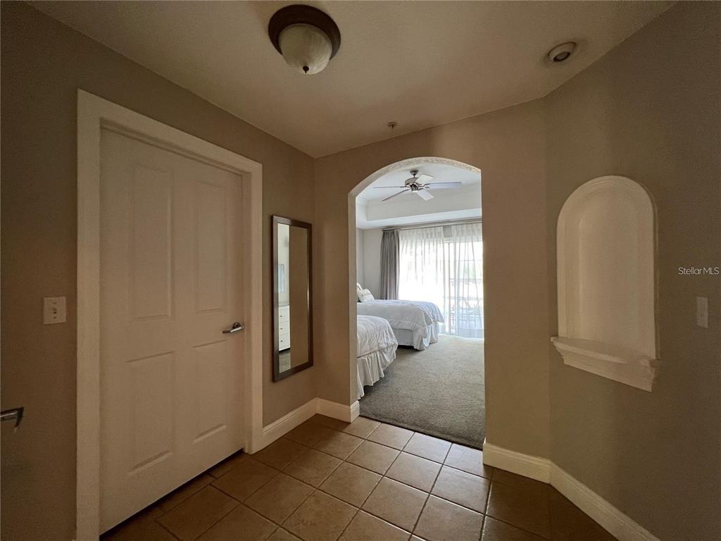 A tiled entryway leads through an arched doorway into a carpeted bedroom with sliding doors — 1301 SEVEN EAGLES COURT UNIT 1301, REUNION, FL