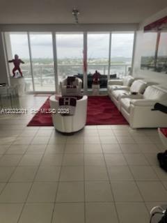 A living room with white tile floors, a red area rug, and white leather furniture — 6301 Collins Ave # 1206, Miami Beach FL 33141, MIAMI BEACH, FL