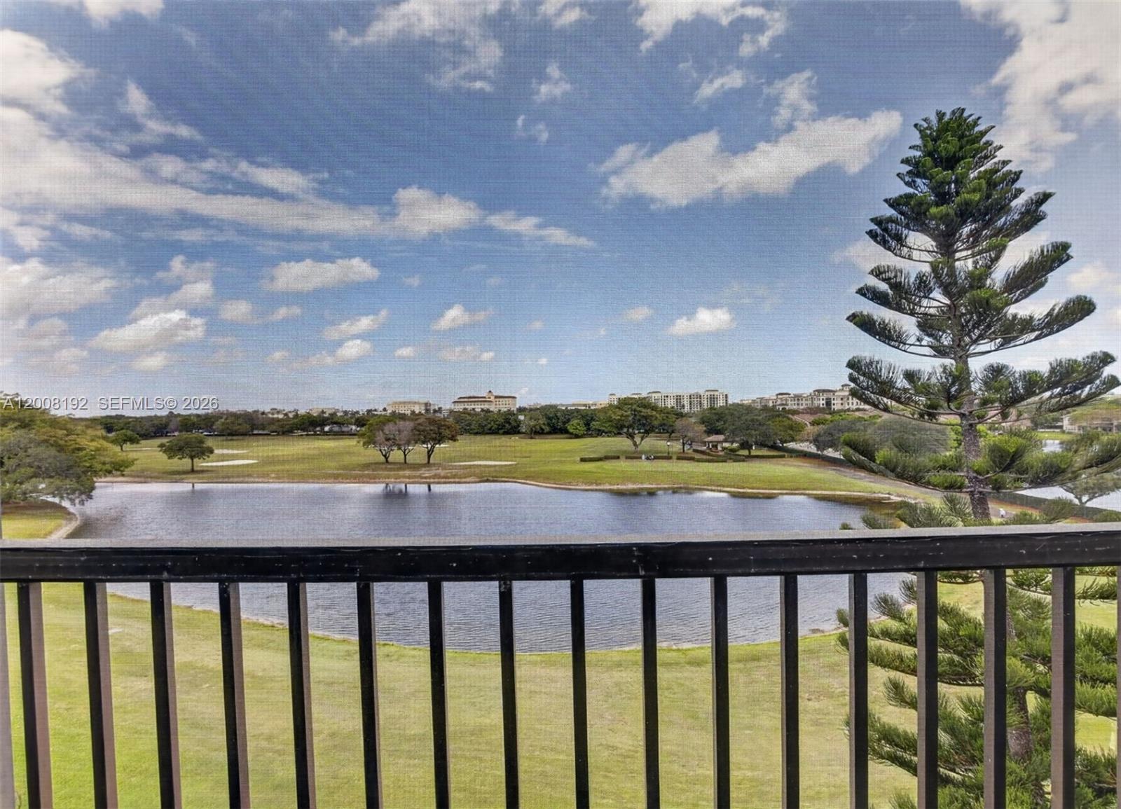 A balcony view overlooks a lake and a golf course with a tall pine tree — 3300 W Rolling Hills Cir # 606, Davie FL 33328, DAVIE, FL