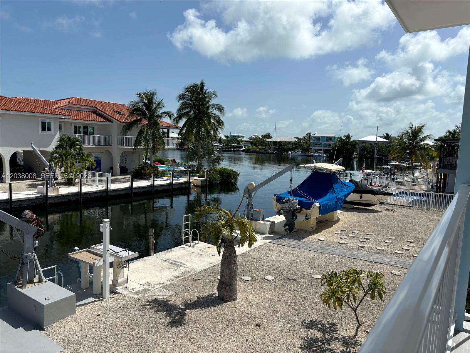 A waterfront property features a boat lift, a canal, and a multi-story house with palms — 9502 Aviation Blvd # 9502, Marathon FL 33050, MARATHON, FL