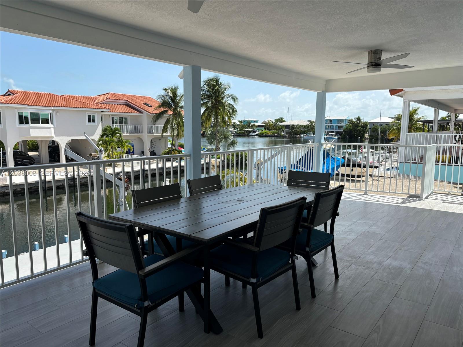 A covered patio features a dining table and chairs overlooking a canal with boats — 9502 Aviation Blvd # 9502, Marathon FL 33050, MARATHON, FL