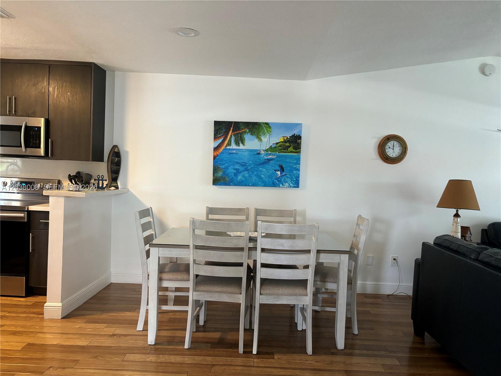 A dining area features a glass-topped table with six chairs, wood flooring, and wall art — 9502 Aviation Blvd # 9502, Marathon FL 33050, MARATHON, FL