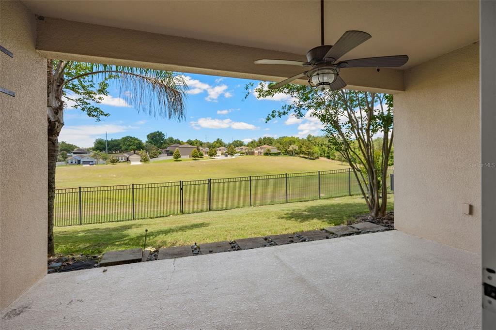 A covered patio with a ceiling fan overlooks a fenced backyard and a grassy field — 30115 KLADRUBY POINT, MOUNT DORA, FL