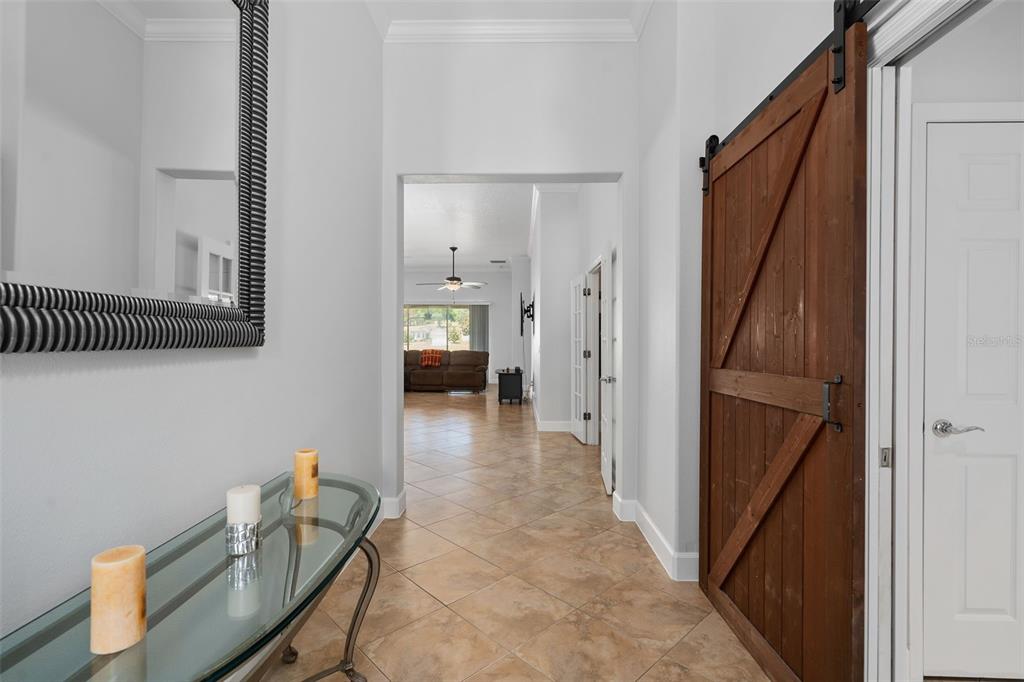 A tiled entryway features a glass console table, a large mirror, and a wooden barn door — 30115 KLADRUBY POINT, MOUNT DORA, FL