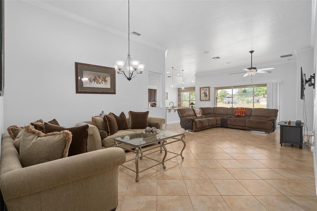 A spacious living room features tile flooring, two brown sofas, and a large sliding glass door — 30115 KLADRUBY POINT, MOUNT DORA, FL