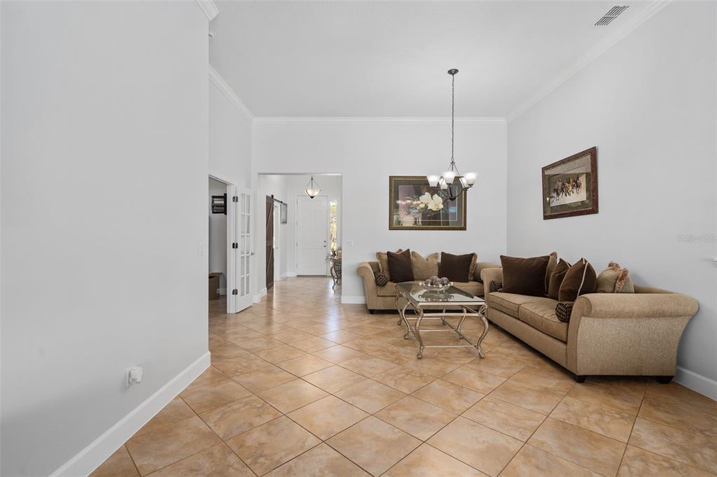 A living room features tan tile floors, two beige sofas, and a central chandelier — 30115 KLADRUBY POINT, MOUNT DORA, FL