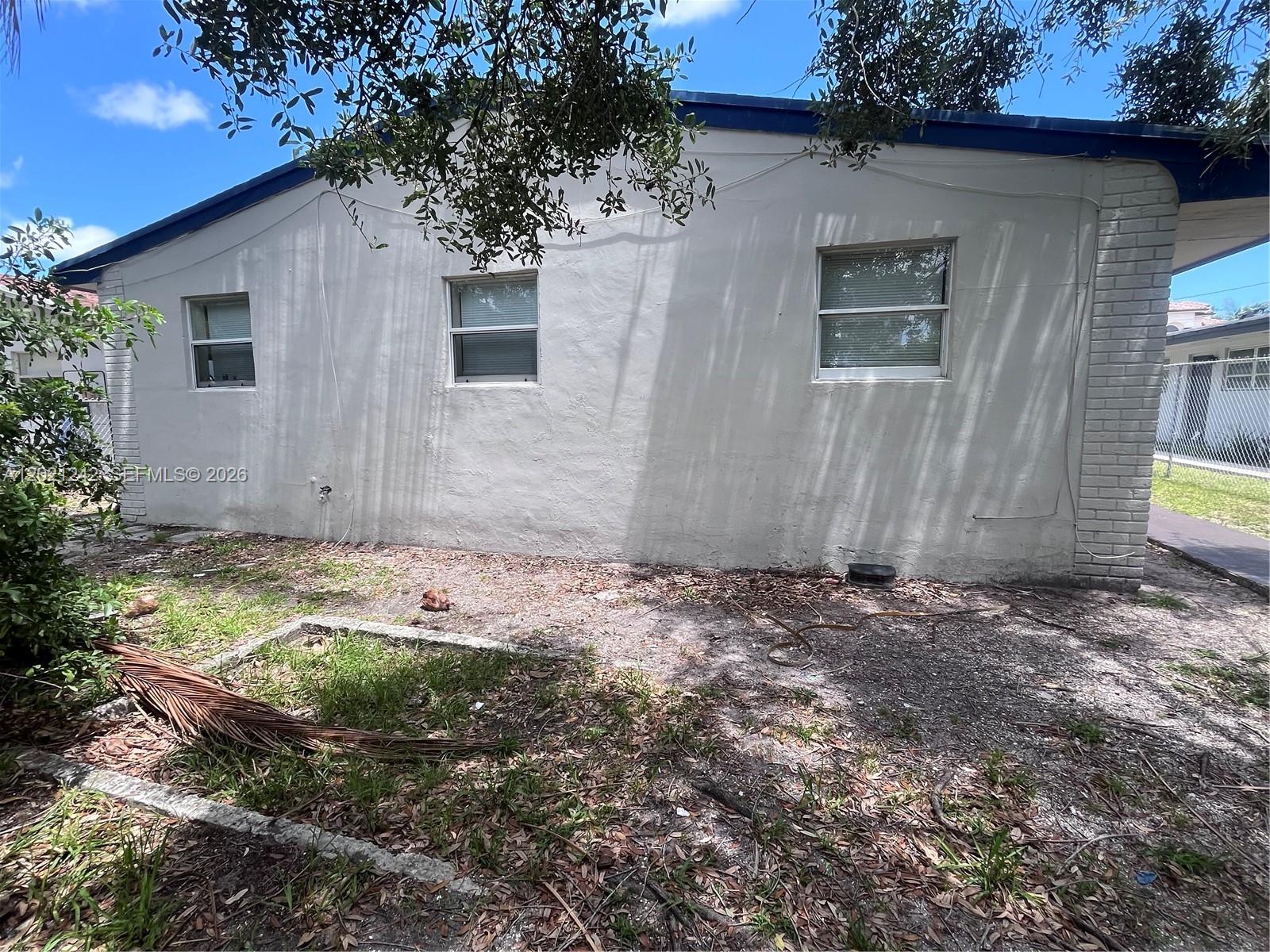 The exterior side of a one-story house features a light-colored wall with three windows — 109 NW 14th Way # 4, Dania Beach FL 33004, DANIA BEACH, FL