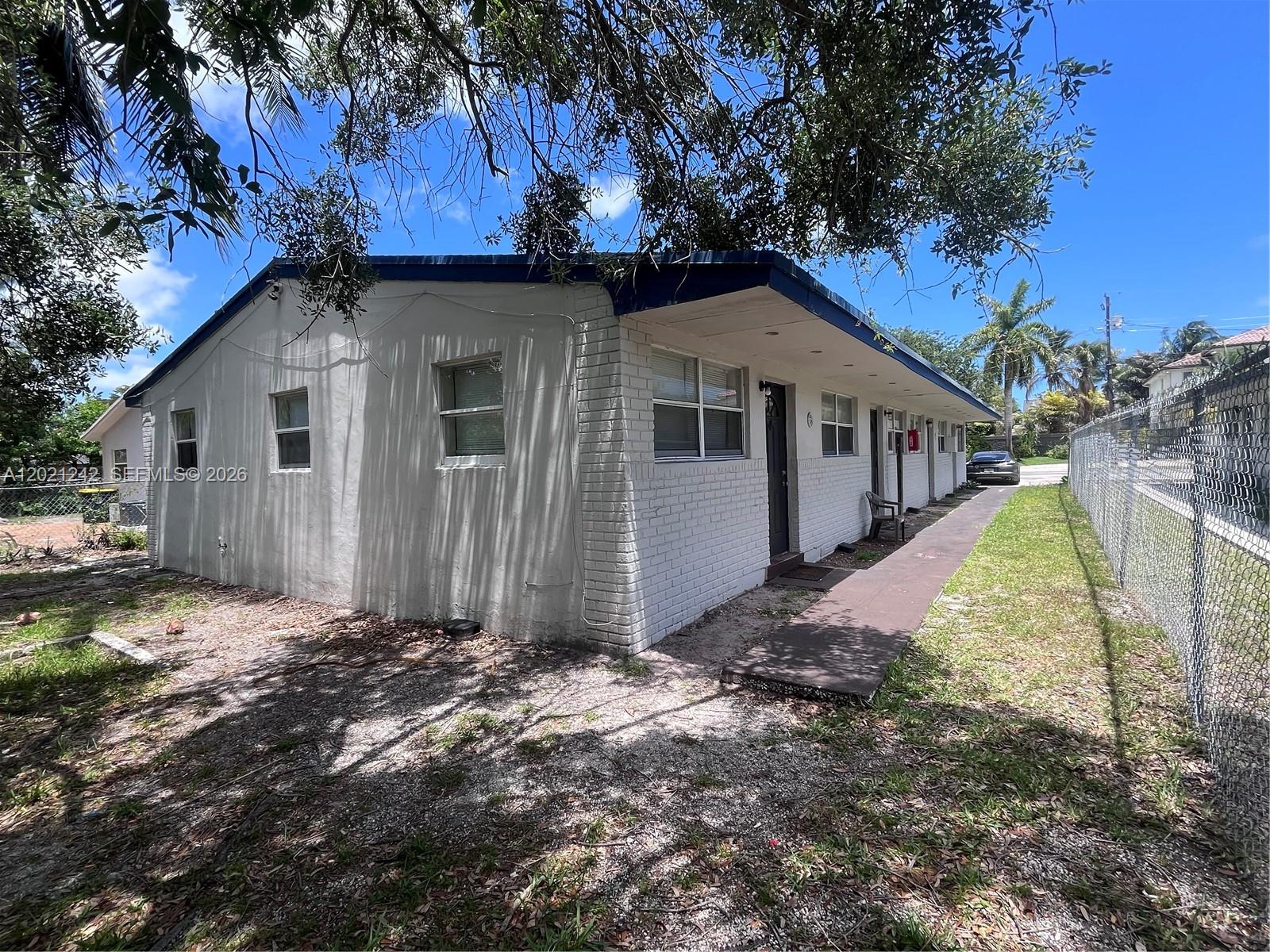 A single-story white brick building features a covered walkway and a chain-link fence — 109 NW 14th Way # 4, Dania Beach FL 33004, DANIA BEACH, FL