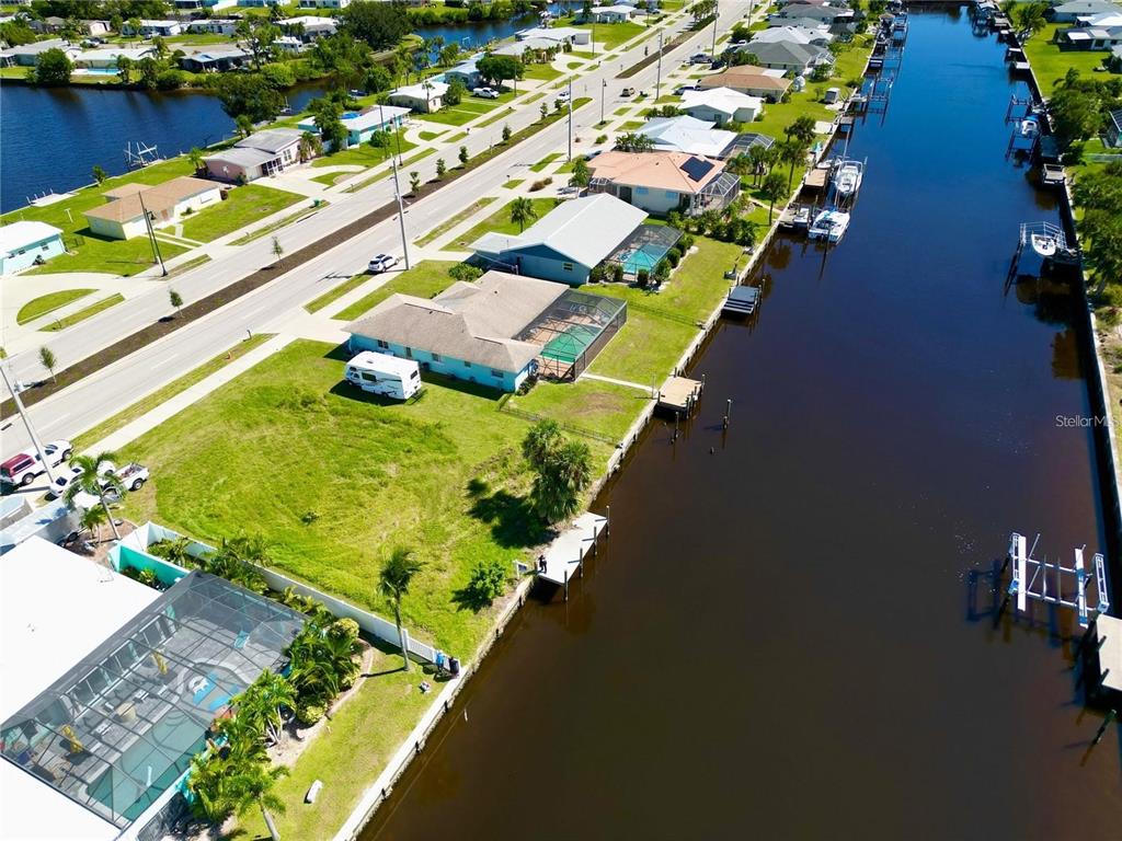An aerial view shows a residential street with houses, a vacant lot, and a canal — 21081 EDGEWATER DRIVE, PORT CHARLOTTE, FL