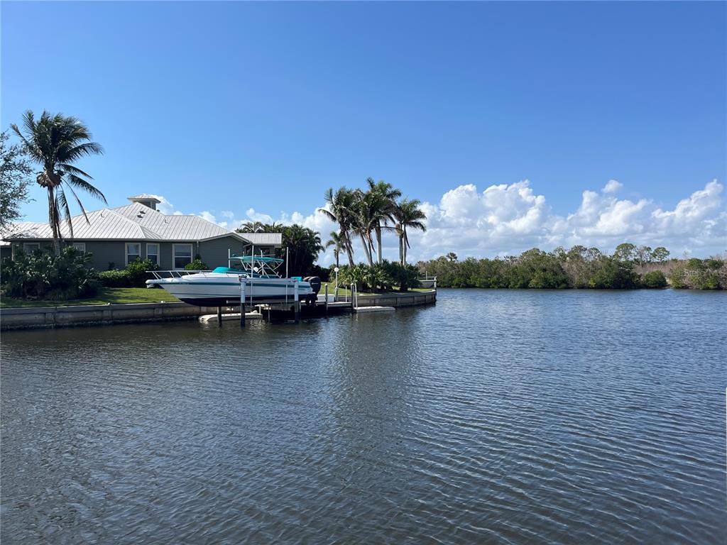 A white boat is docked on a canal next to a house with palm trees — 21081 EDGEWATER DRIVE, PORT CHARLOTTE, FL