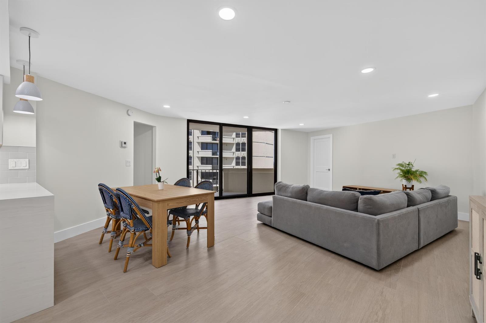 A bright open-concept living and dining area features light wood flooring and a gray sectional — 2800 N Ocean Drive, Riviera Beach FL 33404, RIVIERA BEACH, FL