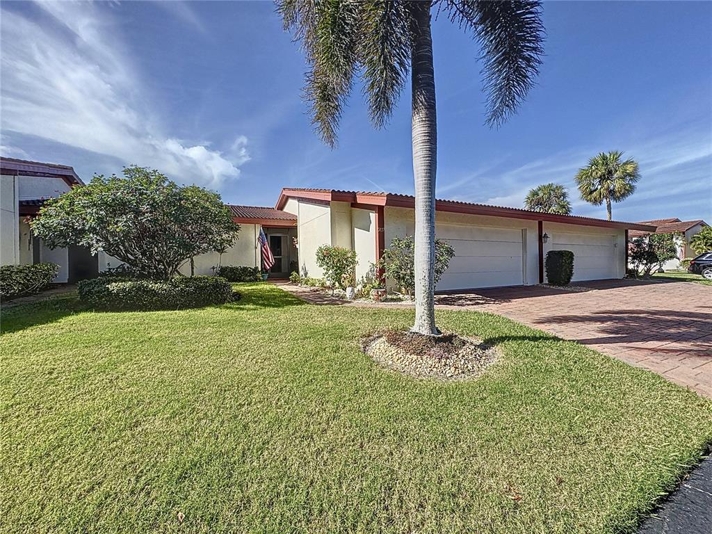 A single-story house with a two-car garage, palm tree, and manicured lawn — 707 SORRENTO INLET UNIT 707, NOKOMIS, FL