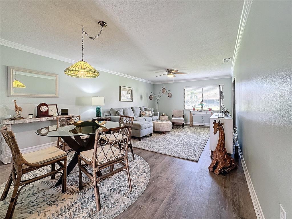 A living and dining area features light green walls, wood-look flooring, and rattan furniture — 707 SORRENTO INLET UNIT 707, NOKOMIS, FL