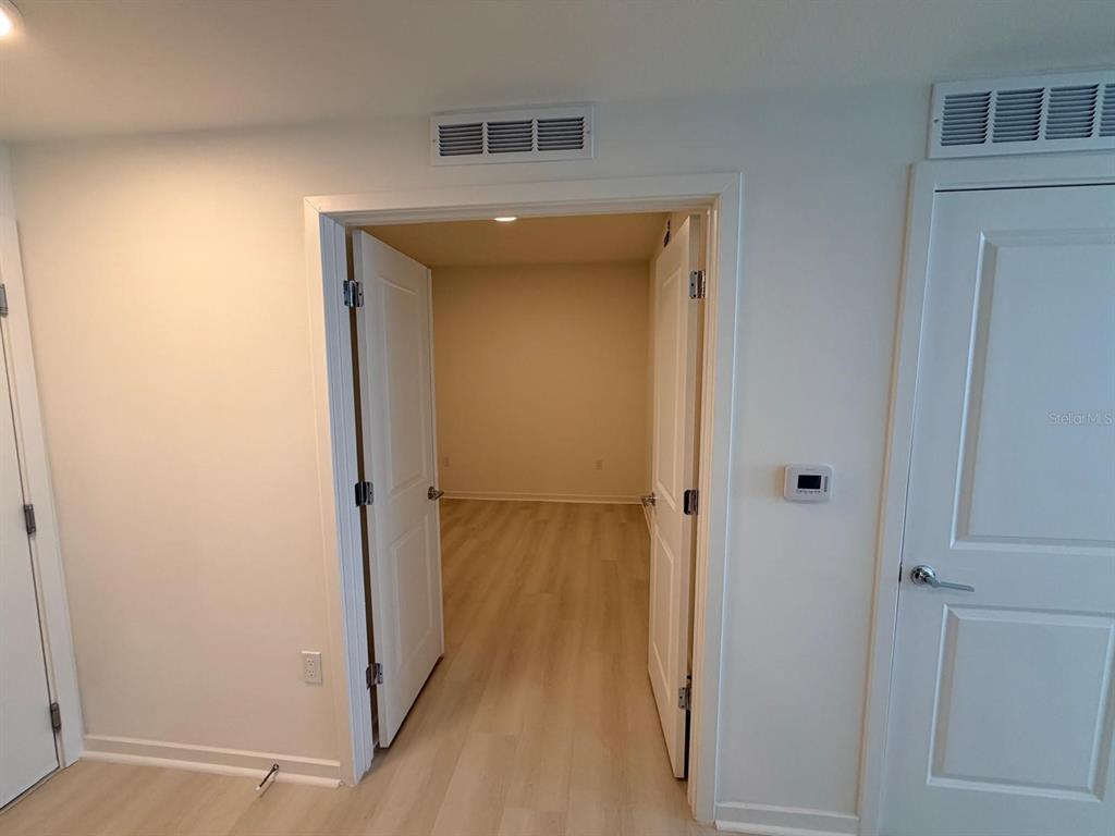 A view through double doors into an empty room with light wood-look flooring — 5587 MILLENIA PARK BOULEVARD UNIT 510, ORLANDO, FL