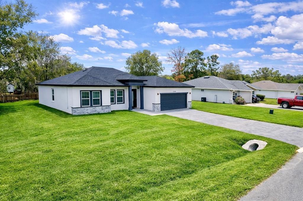 A modern, single-story white house with a dark roof and a paved driveway — 11591 SW 59TH TERRACE, OCALA, FL