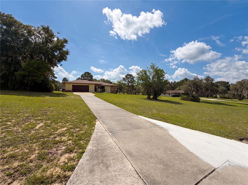 A long concrete driveway leads to a single-story house with a two-car garage — 1641 S VALERIE POINT, INVERNESS, FL