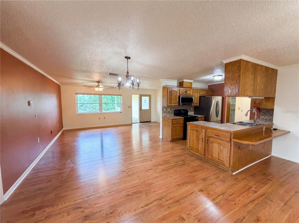 An open-concept kitchen and living area featuring wood-look flooring, oak cabinetry, and a ceiling fan — 1641 S VALERIE POINT, INVERNESS, FL