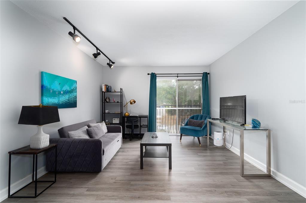A living room features gray flooring, a sofa, a coffee table, and a glass console table — 1700 SW 16TH COURT UNIT C25, GAINESVILLE, FL