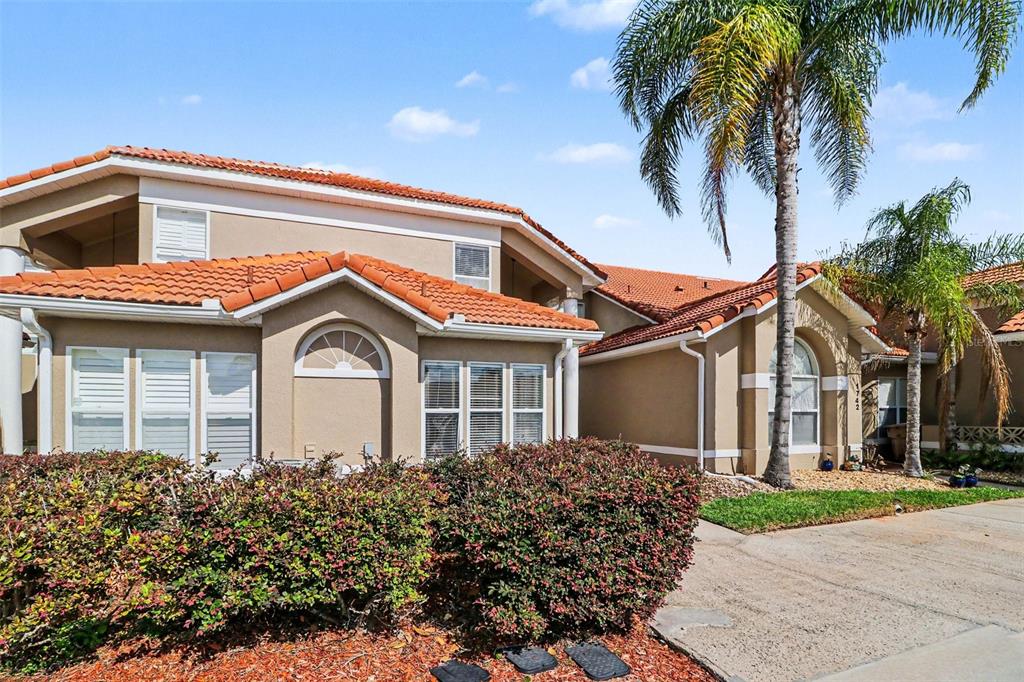 A tan two-story house with a red tile roof and a palm tree in front — 1740 SAINT TROPEZ COURT, KISSIMMEE, FL