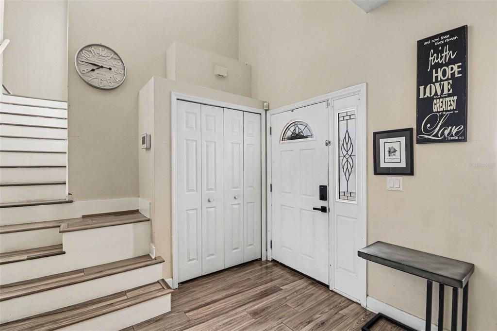 An entryway features a staircase, a white front door, a closet, and wood-look flooring — 1740 SAINT TROPEZ COURT, KISSIMMEE, FL