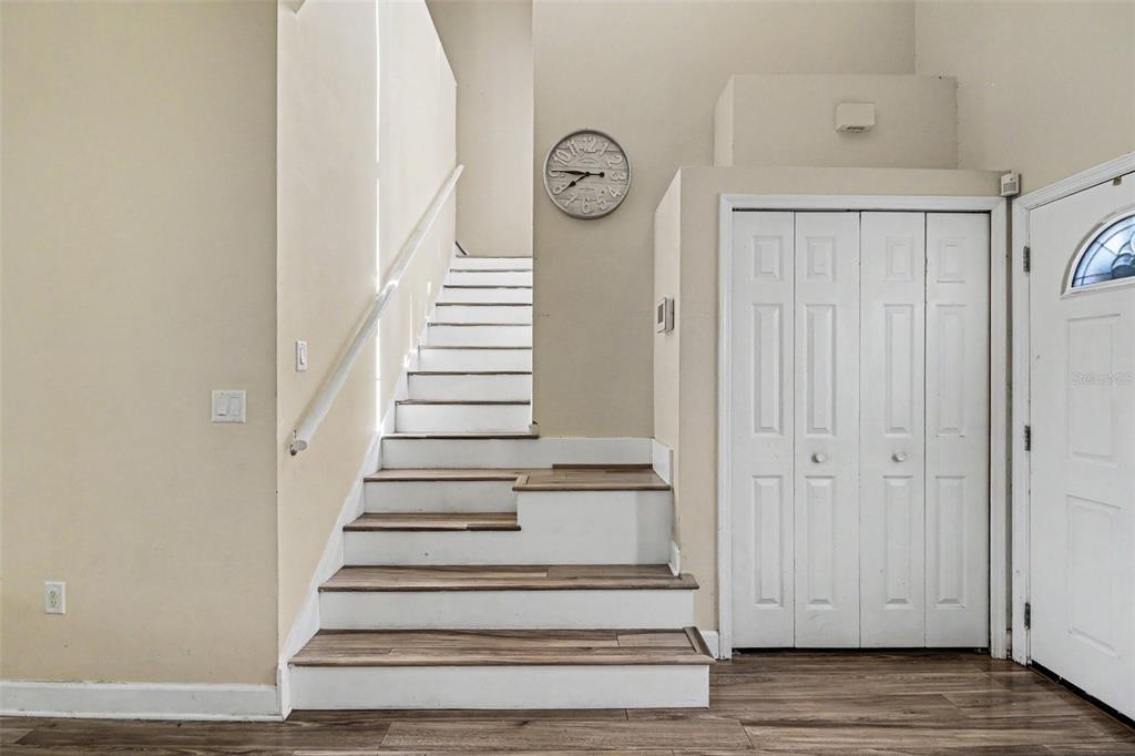 A staircase with wood-look treads and white risers leads upward next to a white closet — 1740 SAINT TROPEZ COURT, KISSIMMEE, FL