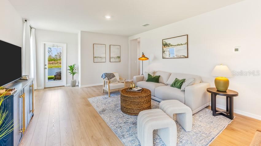 A living room features a light-colored sofa, a woven coffee table, and wood-look flooring — 18117 GANDER TERRACE, LAKEWOOD RANCH, FL