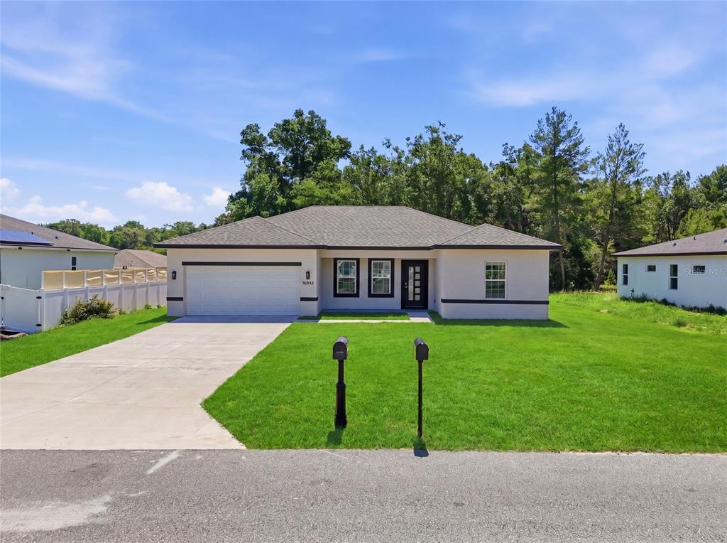A single-story house with a white stucco exterior, a two-car garage, and a front lawn — 16843 SW 18TH AVENUE ROAD, OCALA, FL