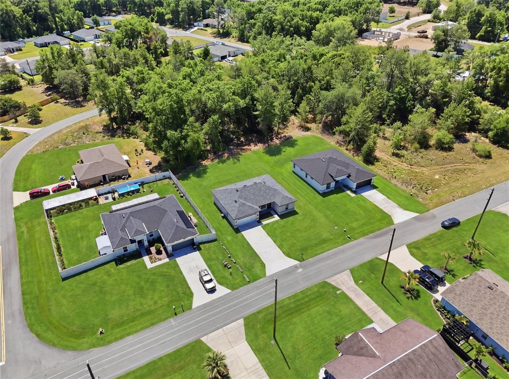 An aerial view shows several suburban houses with driveways and lawns surrounded by dense trees — 16843 SW 18TH AVENUE ROAD, OCALA, FL